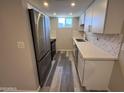 Galley kitchen featuring new stainless steel appliances, marble backsplash and gray wood floors at 2629 W Ocotillo Rd # 3, Phoenix, AZ 85017