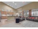 Open-concept living room featuring neutral decor, vaulted ceiling, kitchen, and ample natural light from large windows at 6216 W Morrow Dr, Glendale, AZ 85308