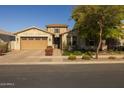 Tan two-story house with a three-car garage and nicely landscaped front yard at 10556 E Relativity Ave, Mesa, AZ 85212