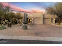 Two-story home with desert landscaping and a three-car garage, showcasing a Southwestern architectural style at 11060 E Mark Ln, Scottsdale, AZ 85262