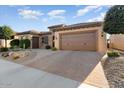 Tan colored house with a brown door and garage doors, plus a nicely landscaped yard at 26783 W Piute Ave, Buckeye, AZ 85396