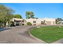 A beautiful stucco home with a large driveway and lush green lawn at 7032 E Dreyfus Ave, Scottsdale, AZ 85254