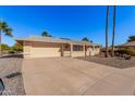 Tan one-story house with a red door, two-car garage, and desert landscaping at 18014 N Broken Bow Ct, Sun City, AZ 85373