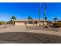 Tan one-story house with a red door, two-car garage, and desert landscaping at 18014 N Broken Bow Ct, Sun City, AZ 85373