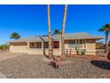 Tan one-story house with a red door, two-car garage, and desert landscaping at 18014 N Broken Bow Ct, Sun City, AZ 85373