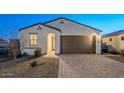 Single-story home with brown garage door and landscaped front yard at 18055 W Muirwood Dr, Goodyear, AZ 85338