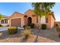 Front view of a one-story house with a brown facade, landscaping, and a two-car garage at 25969 W Tina Ln, Buckeye, AZ 85396