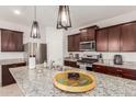 Modern kitchen with dark brown cabinets and granite countertops at 40561 W Hillman Dr, Maricopa, AZ 85138