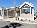 Tan mobile home with covered patio, landscaping, and a paved driveway at 840 S Aquamarine Dr, Apache Junction, AZ 85119