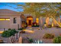 Attractive desert home exterior with well-manicured landscaping at dusk at 10756 E Ludlow Dr, Scottsdale, AZ 85255