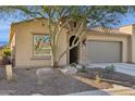 Tan house with a large tree and gravel landscaping at 16955 W Holly St, Goodyear, AZ 85395