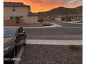 A lovely street view shows homes with desert landscaping, with a mountain backdrop and sunset sky at 32040 N Lisadre Ln, San Tan Valley, AZ 85144