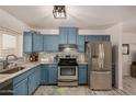 Modern kitchen with blue cabinets, stainless steel appliances, and granite countertops at 1510 E Ironwood Dr, Buckeye, AZ 85326