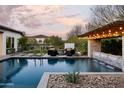 Resort-style backyard featuring a sparkling pool, fire pit, a covered outdoor kitchen and mature landscaping at 29615 N 55Th Pl, Cave Creek, AZ 85331