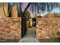 Stone wall entry gate opens to a private courtyard with fountain at 9926 E Hidden Green Dr, Scottsdale, AZ 85262