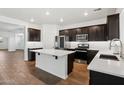 Modern kitchen featuring dark cabinetry, stainless steel appliances, and a kitchen island at 8499 N 174Th Ave, Waddell, AZ 85355