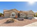 Tan two-story house with a three-car garage and desert landscaping at 15491 W Amelia Dr, Goodyear, AZ 85395