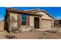 Tan house with red shutters, stone accents, and a paved driveway at 18188 W Fulton St, Goodyear, AZ 85338