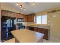 Modern kitchen with dark wood cabinets, black appliances and an island at 19572 N Sandalwood Dr, Maricopa, AZ 85138