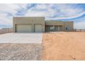 A single-story house with a two-car garage and desert landscaping with a paved driveway on a sunny day at 29340 N 231St Ave, Wittmann, AZ 85361
