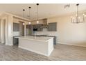 Modern kitchen features a large island, stainless steel appliances, gray cabinets, and stylish pendant lighting at 29380 N 231St Ave, Wittmann, AZ 85361
