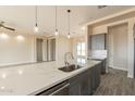 Bright kitchen island with sink and stainless steel dishwasher overlooking multiple rooms through the open concept design at 29380 N 231St Ave, Wittmann, AZ 85361