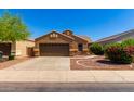 Single-story house with brown exterior, two-car garage, and landscaped front yard at 36532 W Barcelona Ln, Maricopa, AZ 85138