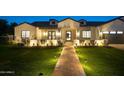 A beautifully lit home at night with a brick facade and landscaped lawn at 5539 E Camelback Rd, Phoenix, AZ 85018