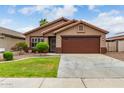 Tan house with brown garage door, well-maintained lawn, and shrubs at 10245 W Jessie Ln, Peoria, AZ 85383