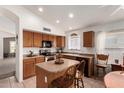 A kitchen featuring wooden cabinetry, a kitchen island with chairs, and modern appliances at 10245 W Jessie Ln, Peoria, AZ 85383