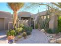Desert landscaping surrounds this stucco home with a circular driveway and gated entry at 10040 E Happy Valley Rd # 1041, Scottsdale, AZ 85255