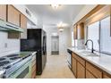 Kitchen with wood cabinets, retro appliances, and tile floors at 10863 W Thunderbird Blvd, Sun City, AZ 85351
