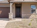 Close-up of the home's entrance featuring a dark wood door and stone veneer accents at 17636 W Pierson St, Goodyear, AZ 85395