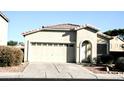 Tan house with a two-car garage and landscaping at 13915 N 132Nd Ln, Surprise, AZ 85379