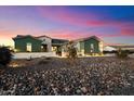 Attractive single-story home with green exterior and stone landscaping at dusk at 338 W Fairfield St, San Tan Valley, AZ 85143