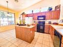 Eat in kitchen with tile floors, center island, oak cabinets and black appliances at 5028 S Peachwood Dr, Gilbert, AZ 85298