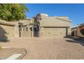 Tan two-story home with a three-car garage and a brick paved driveway at 6202 E Mckellips Rd # 91, Mesa, AZ 85215