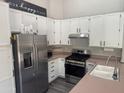 Bright kitchen features white cabinets, stainless steel appliances, and modern gray wood-look flooring at 6703 W Linda Ln, Chandler, AZ 85226