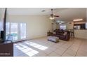 Bright living room with a brown sofa, tile floors, and French doors leading to the backyard at 1643 E Bishop Dr, Casa Grande, AZ 85122
