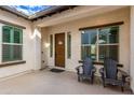 Inviting front porch with two black adirondack chairs and a wooden door at 18346 W Coolidge St, Goodyear, AZ 85395