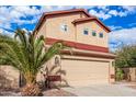 Two-story house with tan exterior, red accents, a two-car garage, and desert landscaping at 6928 E Four Peaks Way, Florence, AZ 85132