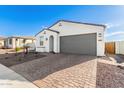 White stucco house with gray garage door and brick driveway at 17765 W Silverwood Dr, Goodyear, AZ 85338