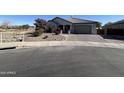 Single-story home with a gray exterior, landscaping, and a paver driveway at 18769 N Falcon Ln, Maricopa, AZ 85138