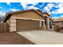 Tan house with a two-car garage and desert landscaping at 20472 N 90Th Ln, Peoria, AZ 85382