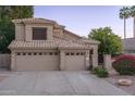 Charming home exterior with tile roof, lush landscaping, and a three-car garage at 5951 W Irma Ln, Glendale, AZ 85308