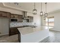 Bright kitchen features stainless appliances, pendant lighting, tiled backsplash, and island with sink at 24235 N 194Th Ave, Surprise, AZ 85387