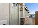 Inviting front door of a home with stone accents and an exterior light fixture at 4380 N 203Rd Dr, Buckeye, AZ 85396