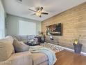 Living room with wood feature wall, sectional sofa, and large TV at 14335 W Country Gables Dr, Surprise, AZ 85379