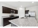 Modern kitchen with dark cabinets, granite countertops, and stainless steel appliances at 1818 W Stradling Ave, Apache Junction, AZ 85120