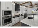 Modern kitchen featuring stainless steel appliances, white cabinets, a sleek black range hood, and marble countertops at 3322 N Valencia Ln, Phoenix, AZ 85018